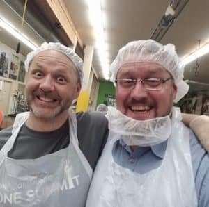 Two men in a warehouse facility wearing hair nets