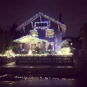 house at night with colorful christmas lights reflecting in a puddle
