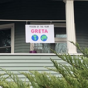 sign in front of house shows globes and Greta Person of the Year